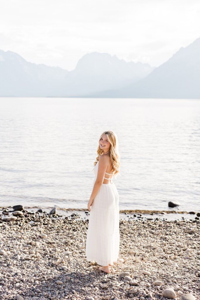 Senior Photos in the Tetons. Girl standing on the beach at Colter Bay in The Grand Teton National Park