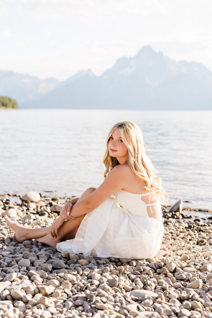 Senior Photos in the Tetons, girl sitting on the beach at Colter Bay